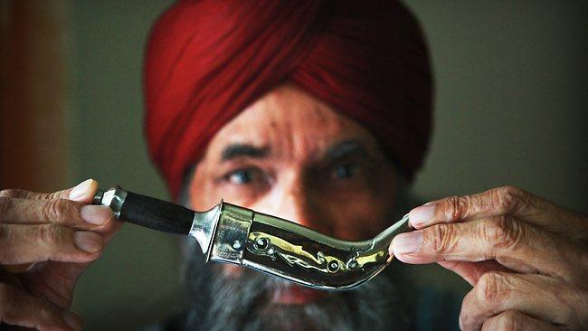 Photo of a Sikh man holding a small Kirpan
